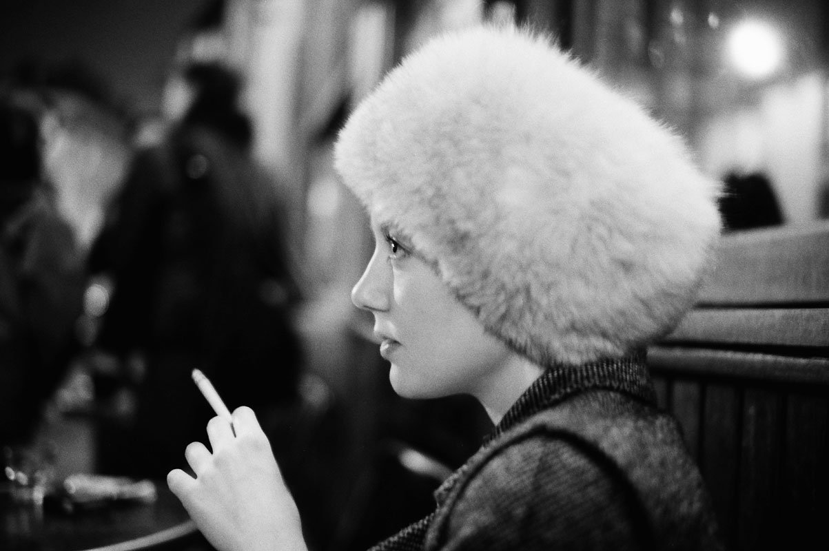 Black and white profile portrait in a fur hat at a cafe