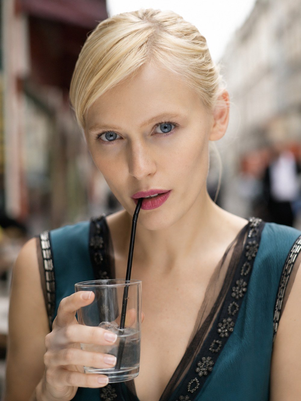 Portrait of a blonde woman sipping an iced drink on a Paris street