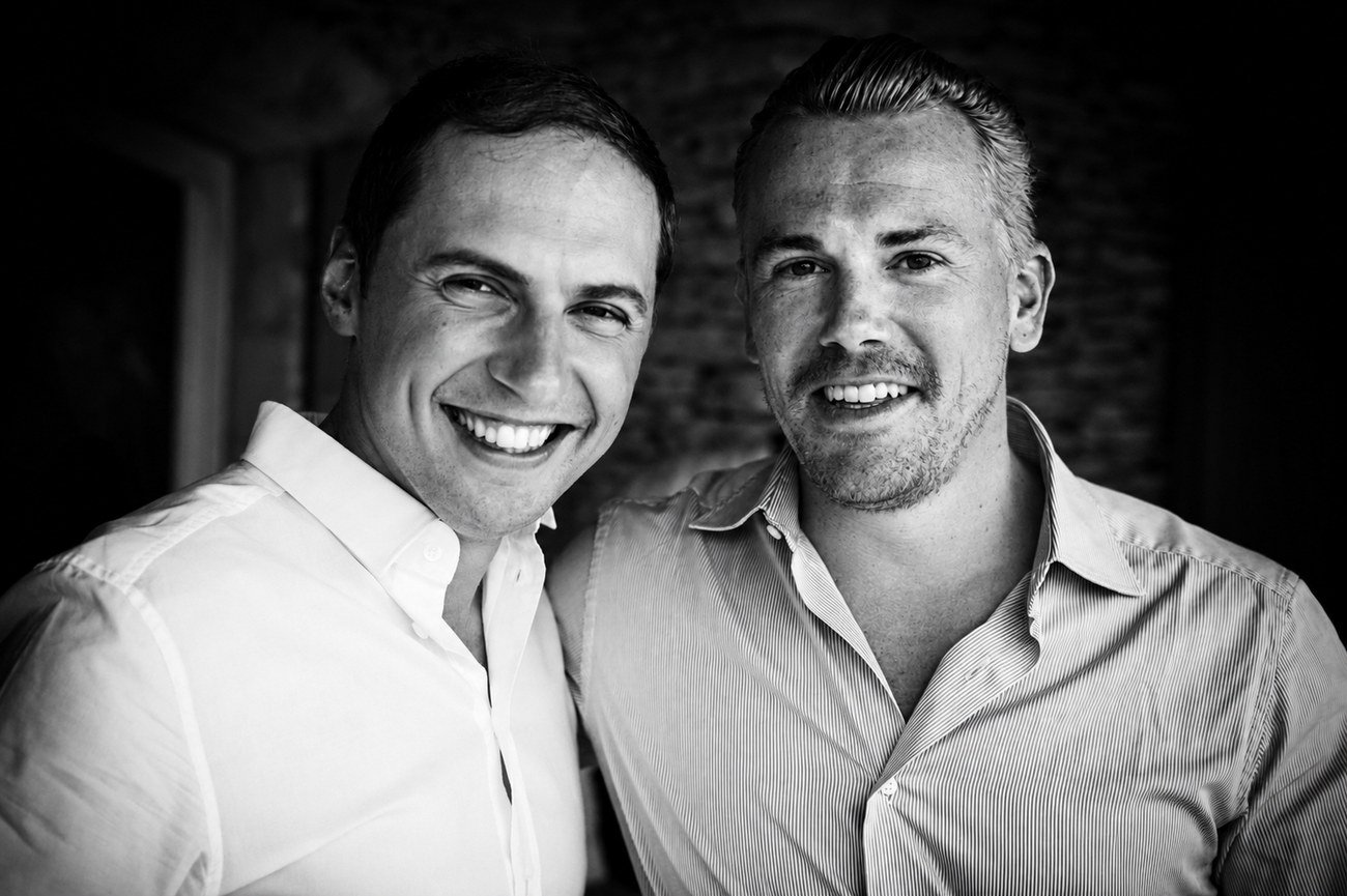 Two groomsmen sharing a laugh, black and white portrait