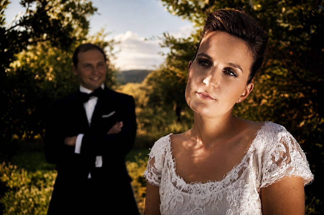Bride portrait in the orchard at golden hour, groom in the background